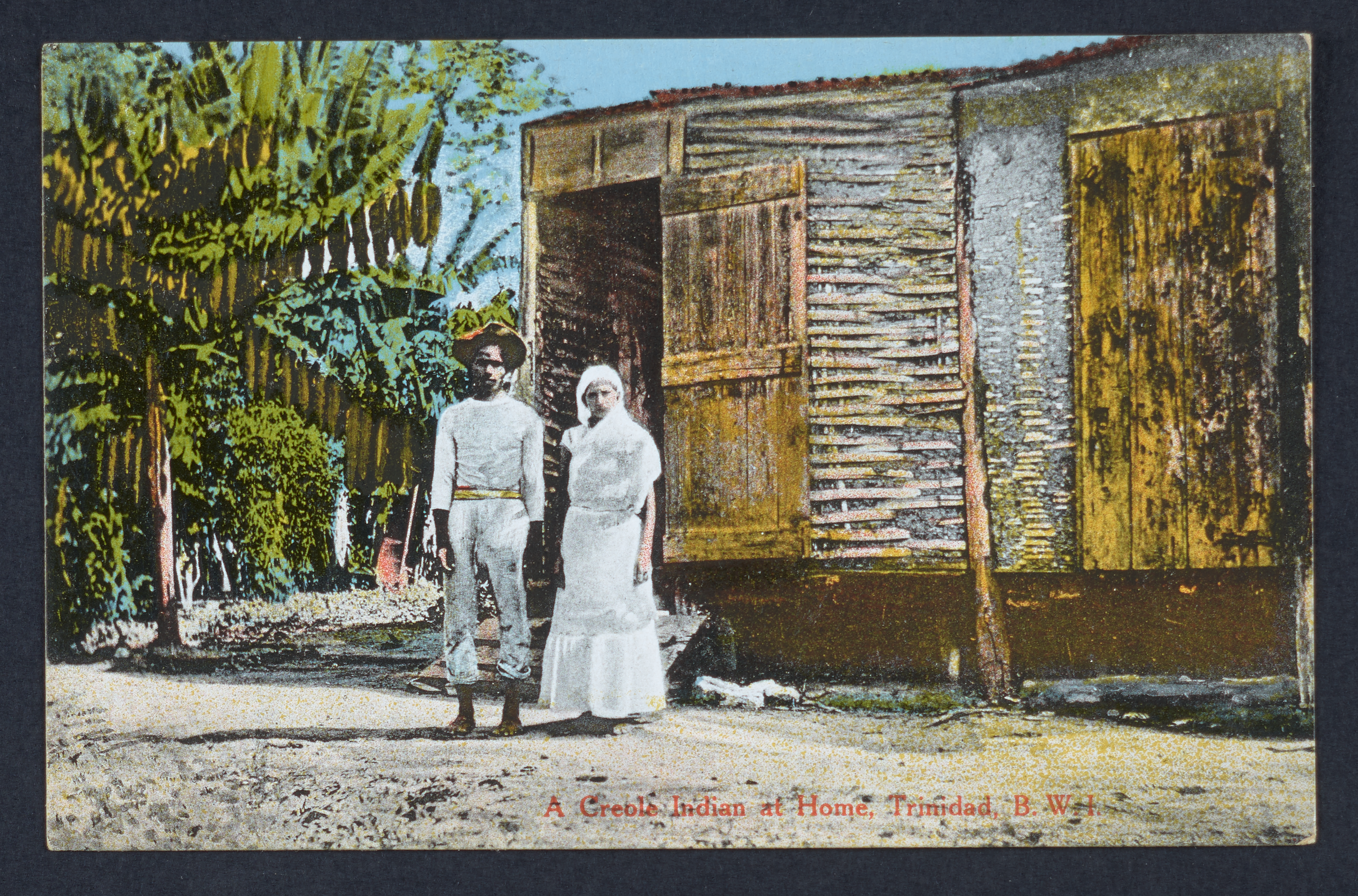 A Creole couple stand in front of their house.